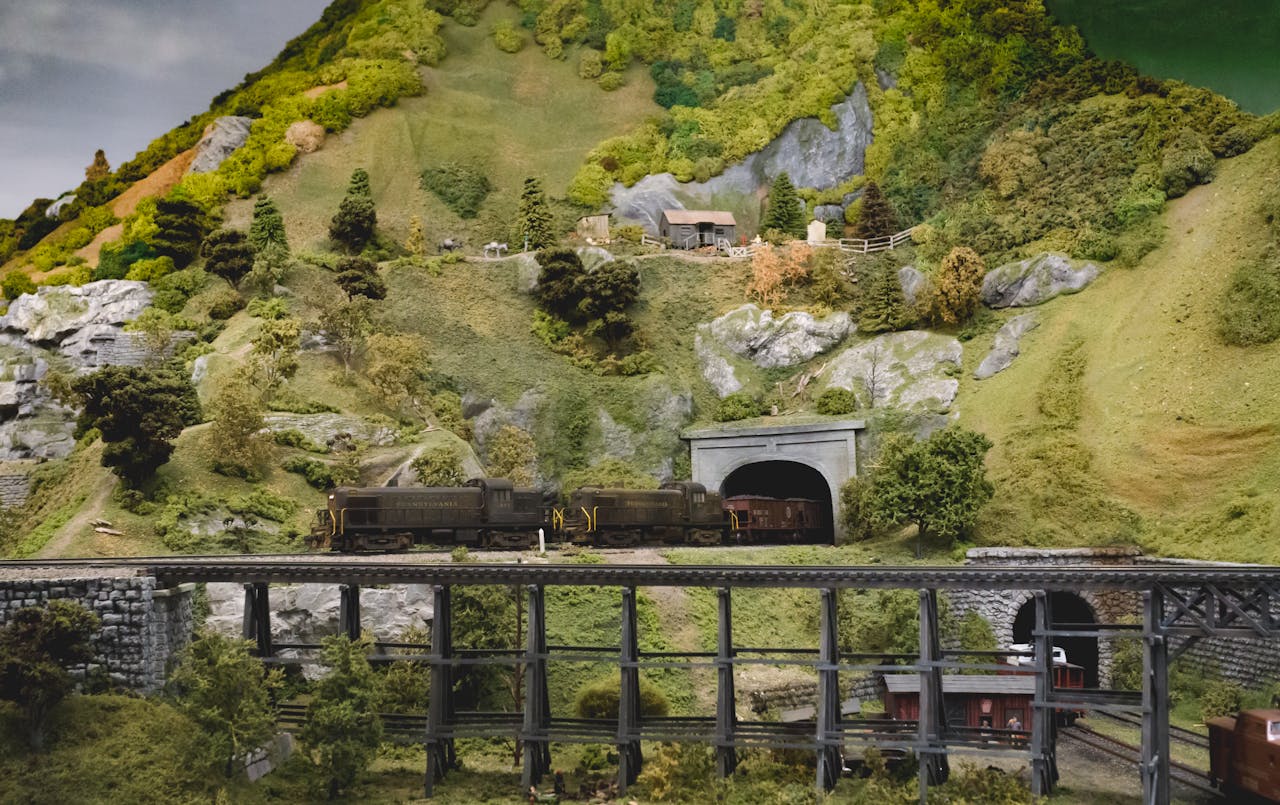 Diorama depicting model train on a bridge through a scenic countryside landscape.